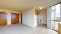 Located in Cudahy, Wisconsin, this single-floor unit offers a practical and straightforward layout designed for comfortable everyday living. The main living area is open and bright, featuring neutral carpet flooring and clean white walls that create a welcoming atmosphere. A partial dividing wall separates the living space from the kitchen, lending a sense of definition while maintaining an open feel.

The kitchen is efficiently arranged and well-equipped, featuring warm honey-toned wood cabinetry both above and below the counter, providing ample storage space. White appliances — including a refrigerator, electric range with oven, and range hood — line the kitchen wall, complemented by light tile flooring and a single-basin sink. The warm cabinet tones add a touch of character to the otherwise clean, neutral palette throughout.

The bathroom is tidy and functional, outfitted with a full soaking tub and shower combination, white subway-style tile surround, and standard fixtures in a bright, all-white finish. The space is designed for easy maintenance and practicality.

The living and sleeping area features rich wood-toned sliding closet doors, offering generous built-in storage. The solid wood entry door adds a classic touch to the unit's overall design. The consistent use of warm wood tones throughout the cabinetry and doors ties the space together cohesively.