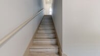 The Canal, Unit A1.5 (02-0107) is a thoughtfully designed one-bedroom, one-bathroom residence spanning 920 square feet across three floors. The layout is distributed with 130 sq ft on the ground floor, 420 sq ft on the first floor, and 370 sq ft on the second floor, connected by three staircase areas. Light wood-style flooring runs throughout, complementing the bright, neutral palette of the space.

The open-concept kitchen and living room on the main level serves as the heart of the unit. The kitchen features white shaker cabinetry, granite countertops, a stone tile backsplash, and a full suite of stainless steel appliances including a range, over-the-range microwave, and refrigerator. A peninsula with a granite surface provides additional prep and dining space.

The living area is generously sized with large floor-to-ceiling windows that flood the space with natural light and offer outdoor views. A ceiling fan adds both function and style.

The 160 sq ft primary bedroom includes its own ceiling fan, large windows with outdoor views, and access to two closets. The bathroom is well-appointed with white cabinetry, granite countertops, a soaking tub, and light tile flooring. A hallway connects the upper-level spaces efficiently, with additional storage provided by two closets throughout the unit.