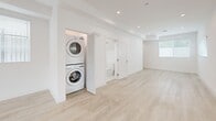 Located at 1301 E 27th St in Los Angeles, this two-story residence offers a clean, modern aesthetic across two well-proportioned floors. The main level hosts an open-concept living area and kitchen, where light wood-style flooring, recessed lighting, and white-framed windows with slatted blinds create a bright, airy atmosphere. The kitchen is equipped with stainless steel appliances—including a gas range, built-in microwave, dishwasher, and refrigerator—complemented by white shaker cabinetry, a subway tile backsplash, and ample counter space. The living area flows naturally from the kitchen, enhanced by large windows that invite natural light.

The upper level houses both bedrooms, each finished with the same light flooring and large windows. The primary bedroom features mirrored sliding closet doors, while the second bedroom offers convenient access to a dedicated closet. A stacked washer and dryer unit is integrated into the upper level for added convenience.

Both bathrooms are finished with marble-style tile flooring, white vanity cabinetry with brushed nickel hardware, undermount sinks, and glass-enclosed showers. One bathroom features dramatic stone-tiled walls, while the other includes an illuminated mirror, lending each a distinct yet cohesive upscale character throughout.