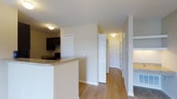 This single-floor residence offers a clean, functional layout designed for comfortable everyday living. The open-concept design connects the kitchen and living areas seamlessly, creating a bright and welcoming atmosphere throughout. The kitchen is equipped with rich, dark cabinetry that provides ample storage, complemented by granite-look countertops that add a touch of elegance to the space. A breakfast bar extends the counter space, making it ideal for casual dining or entertaining. Light-toned, hardwood-style flooring runs throughout the main living areas, lending warmth and continuity to the space. The hallway leads to multiple rooms, each accessible through classic six-panel doors that contribute to the home's traditional character. Closet doors line the corridor, offering generous storage solutions. The neutral wall tones in soft whites and warm beiges create a versatile backdrop that adapts easily to a variety of furnishing styles. Flush-mount ceiling lighting provides consistent illumination throughout. The overall ambiance is clean, modern, and move-in ready, with thoughtful details that balance practicality and style in a compact, efficient floor plan.