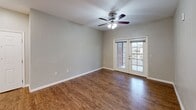 Located at 210 Hunters Crossing Blvd in Bastrop, TX, this single-story, 3-bedroom, 2-bathroom home offers a practical and comfortable layout across a compact but efficiently designed floor plan. The entryway welcomes you with warm wood-look flooring and neutral gray walls that carry throughout much of the home, creating a cohesive and understated aesthetic.

The living room is a bright, open space featuring a ceiling fan and French doors that let in natural light and provide outdoor access. Adjacent to it, the dining area is accented by an elegant multi-bulb chandelier, adding a touch of character to the space. The kitchen is well-appointed with dark espresso cabinetry, light countertops, a double sink, recessed lighting, and black appliances including a refrigerator, range, and microwave — all set on durable wood-look flooring.

The three bedrooms are carpeted for comfort, with ceiling fans in the larger rooms. The spacious primary bedroom includes its own bathroom with a walk-in closet featuring built-in shelving. The second bathroom offers a tiled tub-shower combo, a dark-cabinet vanity, and wood-look flooring. A hallway connects the private areas of the home, completing this functional and well-designed residence.