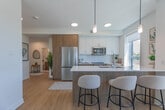 Located at 155 Greenbrier Rd in Cambridge, Ontario, this well-appointed 2-bedroom, 2-bathroom unit offers a thoughtfully designed open-concept layout on a single floor. Light hardwood flooring flows throughout, complementing the clean, modern aesthetic defined by bright white walls and contemporary finishes.

The kitchen is a standout feature, boasting two-tone cabinetry in white and warm wood tones, stainless steel appliances, a large central island with a white quartz countertop and built-in sink, and stylish pendant lighting. Multiple windows flood the space with natural light and offer views of the surrounding landscape. The kitchen opens seamlessly into the dining area and living room, creating an inviting, connected space ideal for daily living and entertaining.

The living room is bright and airy, anchored by a large window framing outdoor views and featuring light hardwood flooring. Both bedrooms are comfortably sized — the primary bedroom is generously proportioned — each with windows, hardwood floors, and a calm, neutral palette. A dedicated closet provides convenient storage.

The two bathrooms are finished in a modern style, featuring warm wood vanities with white countertops, large mirrors, and sliding glass shower enclosures. A hallway connects all rooms efficiently, completing this well-organized and stylish home.