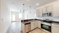 This single-story, 2-bedroom, 2-bathroom residence offers a thoughtfully designed layout that maximizes comfort and functionality. The open-concept kitchen serves as the heart of the home, featuring grey shaker-style cabinetry, dark granite countertops, a peninsula with pendant lighting, and a full suite of stainless steel appliances including a range, microwave, dishwasher, and refrigerator. Light wood-look flooring extends throughout the main living area, creating a seamless flow from the kitchen into the living space, which is equipped with a ceiling fan. Natural light enters through multiple windows and a front entry door with sidelights, giving the space a bright and airy feel. Both bedrooms are carpeted and include ceiling fans, with the primary bedroom offering a dedicated closet. The secondary bedroom features vaulted ceiling accents and a window that brings in additional natural light. Each bathroom is outfitted with a tub/shower combo, wood-look tile flooring, and brushed nickel fixtures, with one bathroom also featuring a granite-topped vanity. Two closets provide ample storage throughout the residence, rounding out a practical and clean living environment.