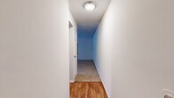 This single-floor residence in Catonsville, MD offers a well-organized layout with four bedrooms, two full bathrooms, a living room, kitchen, dedicated laundry room, and a connecting hallway. The living room is generously sized, featuring plush neutral carpeting and a large sliding glass door that fills the space with natural light and provides views of the exterior. The kitchen is thoughtfully equipped with warm oak cabinetry, granite-toned countertops, a black dishwasher, a full-size refrigerator, a built-in microwave, and a white range — all complemented by wood-look hardwood flooring that extends through the entryway and kitchen area. The four bedrooms are carpeted and offer clean, neutral walls; the primary bedroom is notably spacious, while the secondary bedrooms each feature windows that bring in natural light. Both bathrooms are efficiently designed, with one showcasing mosaic tile flooring, a wood-vanity with a white sink, a wall mirror with overhead lighting, and a shower-tub combo. The dedicated laundry room houses a full-size washer and dryer alongside upper cabinetry for added storage. A central hallway with overhead flush lighting connects the rooms, creating a cohesive and practical flow throughout the home.