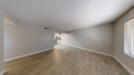 Located at 2301 S Valley View Blvd in Las Vegas, NV, this 2-bedroom, 1-bathroom single-floor unit offers a clean, modern aesthetic throughout. The open living room features light wood-look vinyl flooring, neutral gray walls, crisp white baseboards, and a textured ceiling, creating a bright and welcoming atmosphere. An open passthrough connects the living area to the kitchen, which is well-appointed with white shaker cabinets, a subway tile backsplash, stone-look countertops, and a full suite of stainless steel appliances including a refrigerator, range, and over-the-range microwave. A ceiling fan adds comfort to the kitchen space. The primary bedroom is generously sized, featuring plush carpet, a large window for natural light, and a closet. The second bedroom also offers wood-look flooring, a sizable window with blinds, and ample wall space. Both bedrooms include dedicated closets for storage. The bathroom is finished with marble-style tiled tub and shower surround, wood-look tile flooring, a white vanity with stone countertop, and brushed nickel fixtures. A hallway connects all rooms, completing this efficient and well-designed layout.