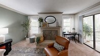 Located in Hoover, Alabama, this well-appointed 2-bedroom, 3-bathroom home offers a thoughtfully designed single-floor layout. The living room serves as the heart of the home, centered around a classic brick fireplace framed by a decorative mantle and flanked by windows that fill the space with natural light, all set atop plush carpeting. Adjacent, the dining room features crown molding, a pendant light fixture, sage-green walls adorned with a curated gallery wall, and wood-look flooring that continues into the kitchen. The kitchen is outfitted with ample taupe cabinetry, light countertops, black appliances including a range, microwave, and dishwasher, plus a stainless steel sink. A central hallway connects the living areas to the two bedrooms, each carpeted and filled with natural light from large windows. The spacious primary bedroom includes a generous walk-in closet with built-in shelving. The second bedroom is equally comfortable with easy closet access. Three bathrooms serve the home, including one with a tub/shower combo and wood-look flooring. Additional highlights include textured ceilings, crown molding in key areas, and a private balcony that extends the living space outdoors.