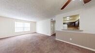 This two-bedroom, two-bathroom single-floor residence in Lyndon, Kentucky offers a functional and comfortable layout. The open living area is finished with plush wall-to-wall carpeting and a textured ceiling, with a large window that draws in natural light and a ceiling fan that enhances air circulation. A pass-through window with a countertop bar connects the living space to the kitchen, which features tile flooring, dark wood cabinetry, a tile backsplash, and white appliances including a range and refrigerator. Both bedrooms are carpeted and equipped with ceiling fans and windows for natural light. The spacious primary bedroom includes a mirrored sliding-door closet, offering ample storage. The second bedroom is equally well-lit with a windowed wall. A connecting hallway links the bedrooms to the two full bathrooms, each featuring a tub-shower combination with white tile surround. One bathroom includes a warm wood-toned vanity with a mirror and wall-mounted lighting. Throughout the residence, a neutral color palette and consistent finishes create a cohesive, move-in-ready atmosphere well suited for everyday living.