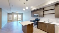 Located at 4901 Broadway in Oakland's vibrant Temescal neighborhood, this modern one-bedroom, one-bathroom residence offers a thoughtfully designed open-concept layout with contemporary finishes throughout. The combined kitchen and living area serves as the heart of the home, featuring light wood-style flooring, soft neutral tones, and a sliding glass door that opens to a private outdoor space, filling the room with natural light and neighborhood views. The kitchen is well-appointed with rich dark-wood cabinetry, white quartz countertops, a center island with pendant lighting, and a full suite of stainless steel appliances including a range, microwave, dishwasher, and refrigerator. A tile backsplash adds a polished finishing touch. The bedroom is carpeted for comfort and features a large picture window that brings in ample natural light, along with a dedicated closet for storage. The full bathroom is clean and modern, finished with large-format tile flooring, a white vanity with a framed mirror, and a shower-tub combination. A dedicated laundry area houses a stacked GE washer and dryer, adding everyday convenience. This well-planned residence combines efficient use of space with modern design elements to create a comfortable and stylish urban home.