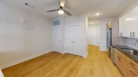 Located at 2200 Pooler Pkwy in Pooler, Georgia, this efficiently designed single-floor unit offers a thoughtfully planned layout that maximizes every square foot. The open-concept living area features light wood-tone flooring, neutral walls, and a ceiling fan with integrated lighting, creating a bright and comfortable atmosphere. A glass-panel door alongside double windows invites natural light and provides direct access to an outdoor space, offering pleasant views of the surrounding community.

The kitchen is a standout feature, showcasing a clean, modern aesthetic with two-tone cabinetry — warm natural wood lower cabinets paired with crisp white upper cabinets — accented by sleek matte black hardware. Dark granite countertops contrast beautifully against a marble-look tile backsplash. Stainless steel appliances, including a range, over-the-range microwave, and dishwasher, complete this functional culinary space.

The bedroom area includes a double-door closet and an additional storage door, offering practical organizational options, with a ceiling fan adding comfort. The bathroom is finished with light wood-tone flooring, a walk-in glass-enclosed shower featuring elegant herringbone-pattern white tile, and brushed nickel fixtures, lending a clean and polished look throughout.