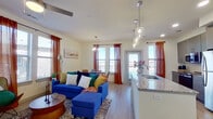 This single-story, 2-bedroom, 2-bathroom residence offers a thoughtfully designed open-concept layout with modern finishes throughout. Light wood-tone flooring flows consistently across the space, contributing to a cohesive and airy feel.

The kitchen serves as a central feature, equipped with gray cabinetry, stainless steel appliances, white subway tile backsplash, and a granite-topped island with an undermount sink. Glass pendant lights hang above the island, adding a refined touch. The kitchen opens directly into the living room, which benefits from multiple windows dressed in warm rust-colored curtains, a ceiling fan, and access to an exterior door.

The primary bedroom offers a comfortable footprint with built-in shelving, dual windows for natural light, a ceiling fan, and direct access to its own bathroom. The bathrooms feature granite countertops, gray vanity cabinetry with gold hardware, and wood-tone flooring. Two closets provide organized storage, including a walk-in closet with built-in shelving and hanging rods. The second bedroom is clean and simply finished, with light-toned walls and wood flooring. Overall, the unit presents a modern, well-lit living environment with functional, contemporary design elements throughout.