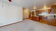 Located at 9215 Zimmerly Ave in Duluth, MN, this well-appointed three-bedroom, two-bathroom single-floor residence offers a functional and comfortable layout. The heart of the home is an open-concept living, dining, and kitchen area, where warm wood cabinetry, a central kitchen island with ample counter space, and stainless steel appliances — including a range and refrigerator — create an inviting and practical space. Hardwood-style flooring in the kitchen transitions seamlessly to plush carpeting in the dining and living areas, which are brightened by natural light and equipped with a ceiling fan. Sliding glass doors lead to a private balcony, extending the living space outdoors. The spacious primary bedroom offers generous proportions and natural light from a large window, while two additional bedrooms also feature carpet, windows with outdoor views, and easy access to closet storage. Four closets throughout the home provide excellent storage capacity. Both bathrooms are finished with tile flooring, a vanity with wood cabinetry, and a tub/shower combination. A dedicated laundry room houses a full-size washer and dryer, adding everyday convenience. A utility room and hallway complete the thoughtfully organized floor plan.