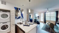 This single-story, one-bedroom, one-bathroom residence in Humble, Texas offers a thoughtfully designed open-concept layout that maximizes functionality. Light wood-style flooring runs throughout the main living areas, creating a cohesive and clean aesthetic.

The kitchen serves as a central feature, equipped with stainless steel appliances including a full-size refrigerator, microwave, and range. Dark wood cabinetry provides ample storage, while the kitchen island with light countertops and pendant lighting offers seating for multiple guests, making it ideal for casual dining and entertaining. The island also includes a single-basin sink with a modern faucet.

The living area flows naturally from the kitchen and receives natural light through large windows dressed with blinds and drapes. The bedroom is well-proportioned, featuring a ceiling fan, large windows with outdoor views, and direct access to a walk-in closet.

The bathroom includes a soaking tub with shower combination, tile surround, light tile flooring, and a vanity with dark wood cabinetry and white countertops. A dedicated walk-in closet is accessible directly from the bathroom. The entry foyer provides a clean transition into the unit, with a louvered closet door and recessed lighting overhead.