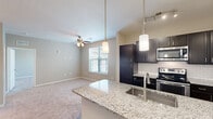 Located in Parker, Colorado, this efficiently designed one-bedroom, one-bathroom residence offers a thoughtful layout with modern finishes throughout. The open-concept living and kitchen area serves as the heart of the home, centered around a granite-topped kitchen island with an undermount sink and elegant pendant lighting. Dark espresso cabinetry contrasts beautifully with the white subway tile backsplash, while stainless steel appliances — including a refrigerator with ice maker, electric range, and built-in microwave — complete the functional yet stylish kitchen. Track lighting and hardwood-style flooring add to the polished aesthetic. The adjacent living area features plush carpeting and a ceiling fan, with a window that brings in natural light. The spacious bedroom offers soft carpeting, a ceiling fan with light fixture, a walk-in closet, and a window overlooking the surrounding community. The full bathroom is finished with a granite-topped dark vanity, wood-style flooring, and a shower-tub combination. A dedicated laundry area houses a full-sized washer and dryer, adding everyday convenience. The overall ambiance is clean, contemporary, and move-in ready.
