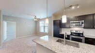 Located in Parker, Colorado, this efficiently designed one-bedroom, one-bathroom residence offers a thoughtful layout with modern finishes throughout. The open-concept living and kitchen area serves as the heart of the home, centered around a granite-topped kitchen island with an undermount sink and elegant pendant lighting. Dark espresso cabinetry contrasts beautifully with the white subway tile backsplash, while stainless steel appliances — including a refrigerator with ice maker, electric range, and built-in microwave — complete the functional yet stylish kitchen. Track lighting and hardwood-style flooring add to the polished aesthetic. The adjacent living area features plush carpeting and a ceiling fan, with a window that brings in natural light. The spacious bedroom offers soft carpeting, a ceiling fan with light fixture, a walk-in closet, and a window overlooking the surrounding community. The full bathroom is finished with a granite-topped dark vanity, wood-style flooring, and a shower-tub combination. A dedicated laundry area houses a full-sized washer and dryer, adding everyday convenience. The overall ambiance is clean, contemporary, and move-in ready.