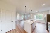 Located at 1061 Dryden Rd in Ithaca, NY, this well-designed two-story home offers a thoughtful layout with modern finishes throughout. The main floor is anchored by a bright, open-concept living, dining, and kitchen area bathed in natural light from multiple windows. The kitchen is a standout feature, showcasing a central island with a white quartz countertop, stainless steel appliances including a refrigerator, range, and built-in microwave, white shaker cabinetry, and stylish matte black pendant lighting overhead. Durable wood-look flooring runs throughout the main living areas, enhancing the clean, contemporary aesthetic. The bedroom is a comfortable retreat, carpeted for warmth, with a ceiling fan and large windows that offer neighborhood views. Ample storage is provided by four closets distributed throughout the home. The full bathroom features a white vanity with a quartz countertop, matte black hardware, a tub/shower combo, and wood-look flooring. Additional highlights include a dedicated laundry area, a staircase connecting the two levels, and an attached garage with an automatic opener, providing convenient parking and extra storage space.