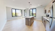 Located at 153 N Sixth St in Newark, NJ, this modern 2-bedroom, 1-bathroom residence offers a thoughtfully designed open-concept layout with contemporary finishes throughout. Light hardwood flooring flows seamlessly across the entire space, lending a clean, cohesive aesthetic.

The open kitchen and living area serves as the heart of the home, anchored by a striking wood-toned island with a crisp white countertop and stylish pendant lighting overhead. The kitchen is well-appointed with light wood cabinetry, a white tile backsplash, stainless steel appliances, and a dedicated window that floods the space with natural light. Large black-framed windows throughout the living area frame neighborhood views and enhance the bright, airy ambiance.

Both bedrooms are well-proportioned, each featuring built-in closets, light hardwood floors, and black-framed windows with outdoor views. The primary bedroom offers a generous footprint with ample closet storage.

The bathroom is finished with a marble-look tile surround in the tub-shower combo, a wood-toned vanity with a round mirror, and large-format floor tiles, creating a clean and polished feel. Recessed lighting and neutral gray walls complete the modern, move-in-ready appeal of this well-designed Newark residence.