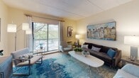 This single-floor residence at 50 Commons Dr in Shrewsbury, Massachusetts offers a thoughtfully organized layout across several distinct living areas. The living room serves as a welcoming central space, featuring a large sliding glass door that opens to a private balcony, allowing natural light to fill the room and providing views of the surrounding greenery. The seating area is comfortably sized, with warm neutral wall tones throughout.

The kitchen is efficiently designed with white cabinetry extending to the upper walls, granite-style countertops, a stainless steel refrigerator, dishwasher, and ample storage. Light tile flooring completes the functional workspace.

The residence includes multiple bedrooms, each offering natural light through well-sized windows, carpeted floors, and generous closet space. The primary bedroom features an expansive row of built-in closets, while additional bedrooms provide dresser-height storage units and comfortable proportions.

Two bathrooms serve the residence: one featuring a tub-shower combination with white tile surround, and a second with a shower-curtain enclosure, white vanity cabinetry, and tile flooring. The overall ambiance throughout is bright, neutral, and cohesive.