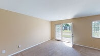 Located in Fort Mitchell, Kentucky, this single-floor unit offers a practical and comfortable layout designed for everyday living. The living room is a generously sized, light-filled space featuring neutral-toned carpet, warm beige walls, and a sliding glass door that opens directly to a private outdoor patio, providing pleasant views of the surrounding greenery. Adjacent to the living area, the dining space is defined by a stylish overhead pendant light and a window dressed with horizontal blinds that allows natural light to filter in, creating a bright and welcoming atmosphere. The kitchen is a standout feature of the unit, showcasing rich dark wood cabinetry extending to the upper walls, granite-style countertops, a mosaic tile backsplash, and black appliances including a range, dishwasher, and refrigerator, all set over durable wood-look flooring. A carpeted hallway connects the remaining rooms, which include well-proportioned bedrooms finished with the same neutral carpet and warm wall tones. The overall ambiance throughout the space is clean, cohesive, and move-in ready, with consistent warm beige tones and ample natural light contributing to an inviting and functional residential environment.