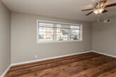 This single-floor home offers a thoughtfully designed layout with a mix of rich hardwood flooring and plush carpeting throughout. The open living areas are finished with warm-toned hardwood floors and neutral wall colors, creating a bright and inviting atmosphere. Large multi-pane windows allow generous natural light to fill these spaces, while ceiling fans provide year-round comfort.

The kitchen is well-equipped and functional, featuring crisp white shaker-style cabinetry, granite countertops, and a full suite of white appliances including a refrigerator, electric range, built-in microwave, and dishwasher. A window above the sink brings in natural light and adds to the kitchen's airy feel.

The bedrooms are finished with soft carpeting and each includes a ceiling fan and windows that overlook the surrounding exterior. Ample closet space is provided, and the neutral tones throughout create a versatile canvas for any décor style.

The bathroom is clean and straightforward, featuring a tub-shower combination, a window for natural ventilation, hardwood flooring, and a white vanity. White walls and fixtures contribute to a fresh, well-maintained appearance throughout. Overall, the space presents a practical and comfortable living environment with consistent finishes across every room.
