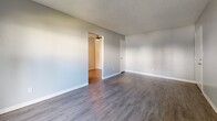 This contemporary apartment, situated at 7833 La Riviera Dr in Sacramento, CA, offers a blend of modern aesthetics and functional design. The space is characterized by its open floor plan, creating a seamless flow between living areas. Neutral gray walls throughout provide a calm backdrop, complemented by durable wood-look flooring that adds warmth and practicality.

Natural light is abundant, thanks to strategically placed windows and a sliding glass door that leads to an outdoor area, enhancing the sense of spaciousness. The kitchen, while compact, is efficiently designed with updated appliances, including a stainless steel refrigerator and oven. White cabinetry contrasts nicely with the dark appliances, offering ample storage.

The bathroom features a clean, white design with a combined tub and shower unit, and modern fixtures. The apartment's layout includes distinct areas that can serve as living room, dining area, and bedroom spaces, allowing for versatile furnishing options.

A standout feature is the textured ceiling, adding visual interest to the otherwise minimalist design. The overall ambiance is one of contemporary comfort, ideal for those seeking a modern living space in an urban setting.