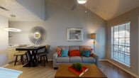 This single-story residence offers a thoughtfully designed layout that balances comfort and functionality across its key living spaces. The living area immediately impresses with its dramatic vaulted ceiling, which lends an open, airy quality to the room. A ceiling fan with integrated lighting anchors the space above, while large windows with blinds allow natural light to filter in. Wood-look flooring in a herringbone pattern adds a refined touch, and a glass-paneled door provides access to the outdoors. A small dining nook with a bistro-style table and chairs completes the living area. The galley-style kitchen is efficiently organized with white cabinetry, light stone countertops, gray tile backsplash, and stainless steel appliances, including a range, refrigerator, and dishwasher. Light wood-look flooring continues the cohesive aesthetic. The bedroom is carpeted and features a textured ceiling with a ceiling fan, a generous window for natural light, and ample space for a full dresser and nightstands. The full bathroom is clean and functional, offering a tub-shower combination, a wide vanity with white cabinetry and light countertops, and a large mirror with overhead storage. Together, these spaces create a cohesive and inviting home environment.