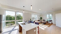 Located at 329 E College Ave in Appleton, WI, this thoughtfully designed 2-bedroom, 2-bathroom residence offers a bright, modern living experience across a single floor. The open-concept kitchen and living area serves as the heart of the home, featuring a sleek center island with a built-in sink, pendant lighting, taupe cabinetry, a white tile backsplash, and stainless steel appliances. Light wood flooring flows throughout, complementing the clean, neutral palette. Expansive windows flood the living area with natural light and frame views of surrounding greenery, creating an airy, welcoming atmosphere. The spacious living room provides generous room for seating and relaxation. The primary bedroom is a comfortable retreat with a large window and a sliding-door closet, while the second bedroom mirrors the same clean aesthetic. Both bedrooms feature light wood flooring and ample natural light. The bathrooms are well-appointed, with one featuring accessibility accommodations including grab bars and a roll-in shower with a fold-down seat. A dedicated in-unit laundry room adds everyday convenience. Additional storage is provided through multiple closets, making this a highly functional and well-organized residence.
