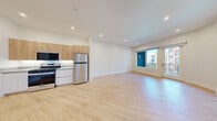 Located at 5050 W Russell Rd in Las Vegas, NV, this modern one-bedroom, one-bathroom unit offers a thoughtfully designed open-concept layout with a seamless flow between the kitchen, dining, and living areas. Light wood-look flooring runs throughout, complementing the crisp white walls and recessed lighting that keep the space bright and airy.

The kitchen is well-appointed with stainless steel appliances — including a gas range, over-the-range microwave, and full-size refrigerator — paired with warm wood upper cabinetry and clean white lower cabinets topped with a sleek countertop. A dedicated wet bar area with open wood shelving, a stainless sink, and an integrated dishwasher adds additional functionality. In-unit laundry is conveniently tucked nearby.

The living area opens directly onto a private balcony through sliding glass doors, filling the room with natural light and offering views of the surrounding community. The spacious bedroom features a cool gray accent wall, large windows with balcony access, and generous closet space. The bathroom is elegantly finished with a wide floating vanity, a backlit mirror, and a glass-enclosed shower, all tied together with the same light wood flooring found throughout the unit.