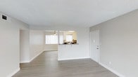 Located at 4300 Echo Ct in La Mesa, Unit 42D is a single-floor residence designed with an open, airy layout that maximizes the sense of space throughout. The living area features smooth, light-toned laminate flooring that extends seamlessly across the space, complemented by clean white walls and crisp white baseboards that give the interior a fresh, modern feel. A ceiling fan is positioned in the living area, providing both functionality and a touch of casual comfort. Natural light flows generously into the space through large windows dressed with vertical blinds, brightening the interior throughout the day. The kitchen is defined by a peninsula-style counter with a breakfast bar overhang, creating a natural divide between the cooking and living areas while maintaining an open-concept feel. The kitchen includes a sink, overhead lighting, and cabinetry in a neutral finish, offering practical functionality. The textured ceiling adds a subtle architectural detail throughout the home. A private entry door is conveniently located within the main living space. Overall, Unit 42D presents a clean, well-lit, and efficiently designed single-level home with a cohesive neutral palette and modern touches throughout.