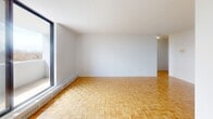 Located at 50 Burn Hill Rd in Toronto's east end, this one-bedroom unit offers a well-organized layout across a single floor. The living area is generously proportioned, featuring warm parquet flooring in a classic basket-weave pattern and large floor-to-ceiling sliding doors that flood the space with natural light and provide access to a private balcony with outdoor views. The clean white walls and bright ceiling create an open, airy ambiance throughout.

The kitchen is thoughtfully appointed with stainless steel appliances, including an electric range and an over-the-range microwave, complemented by white subway tile backsplash and white cabinetry. The kitchen connects seamlessly to the main living area through an open archway, enhancing the sense of flow and connectivity.

The bedroom is a comfortable, well-proportioned room featuring the same parquet flooring and a large window that allows natural light to fill the space. Built-in sliding closet doors provide ample storage. A staircase is also included in the layout, indicating additional access within the building. Overall, this unit presents a clean, functional, and bright living space suitable for those seeking a practical home in Toronto.