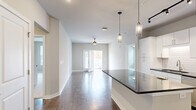 Located at 128 Mill St in Clayton, NC, this well-appointed 2-bedroom, 2-bathroom residence offers a thoughtfully designed single-level floor plan. The open-concept kitchen and living area serves as the heart of the home, featuring rich hardwood-style flooring, sleek white cabinetry, dark countertops, subway tile backsplash, and stainless steel appliances including a side-by-side refrigerator. Stylish pendant lighting illuminates the kitchen island, while a ceiling fan and an exterior door with access to outdoor views complete the bright, airy living space. Both bedrooms are carpeted and generously sized, each equipped with ceiling fans and ample natural light from well-placed windows. The spacious primary bedroom connects to a dedicated walk-in closet with built-in wire shelving and an en-suite bathroom featuring a dual-sink vanity with dark stone countertops, a large mirror, wood-style tile flooring, and a separate shower. The second bathroom offers a full tub-shower combination with classic white subway tile surround, a single-sink vanity, and matching wood-style tile flooring. A hallway with two closets provides additional storage throughout this clean, contemporary residence in the heart of Clayton.
