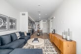 Located at 12888 Crenshaw Blvd in Hawthorne, CA, this thoughtfully designed one-bedroom, one-bathroom residence offers a modern aesthetic throughout. Light wood-tone flooring flows seamlessly across the entire floor plan, complementing the crisp white walls and creating a clean, cohesive look.

The entrance welcomes you with gallery-style framed artwork and a stylish open shelving unit, setting an inviting tone. The combined kitchen and living area serves as the heart of the home. The kitchen is well-appointed with gray shaker cabinetry, stainless steel appliances including a gas range, microwave, and French door refrigerator, a tile mosaic backsplash, and a quartz-topped island with bar seating. The living area offers generous natural light through large windows with open outdoor views.

The bedroom features a bright window overlooking the surrounding skyline, providing an airy and restful retreat. The bathroom is finished with a tiled tub-shower surround, gray vanity cabinetry, and modern fixtures. Additional highlights include two closets for ample storage and a dedicated laundry area. The unit combines functional layout with contemporary finishes, making it a well-rounded residential space in the South Bay area of Los Angeles.