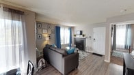 This single-story, 2-bedroom, 2-bathroom residence offers a thoughtfully designed layout with consistent finishes throughout. The living room serves as the central gathering space, featuring wood-style plank flooring, a tile-surround fireplace, and multiple windows dressed with bold blue curtains that invite natural light. A textured ceiling adds character throughout the common areas.

The kitchen is designed for functionality, featuring white cabinetry, gray speckled countertops, stainless steel appliances including a refrigerator, microwave, and electric range, and a double-basin sink. The galley-style layout maximizes efficiency and storage.

Adjacent to the kitchen, the dining area accommodates a full-size table and is accented by a multi-bulb chandelier, creating an inviting space for meals and entertaining.

Both bedrooms are carpeted and equipped with ceiling fans. The primary bedroom includes a walk-in closet, while the second bedroom features large windows with ample natural light. Each bathroom is outfitted with white vanity cabinetry, gray speckled countertops, an oval undermount sink, and a shower-tub combination, maintaining a cohesive aesthetic across the unit.