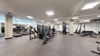 Located at 31 Farmstead Road in Toronto, this well-appointed exercise room offers a substantial, open-plan fitness facility designed to accommodate a wide range of workout routines. The space features durable rubber tile flooring throughout, providing both safety and comfort underfoot, while a clean white ceiling with recessed panel lighting ensures bright, even illumination across the entire floor.

Structural columns are integrated throughout the layout, adding an architectural character to the space without impeding functionality. Along one side, a row of modern treadmills equipped with individual digital screens lines the windowed perimeter, benefiting from natural light that filters in through high clerestory windows. The cardio section transitions seamlessly into a dedicated strength training area, where multiple multi-station cable and resistance machines are thoughtfully arranged to maximize floor space and traffic flow.

A full dumbbell rack provides a comprehensive free weights selection, complemented by benches and a functional trainer tower. An adjacent glass-walled room, visible from the main floor, offers a lounge or breakout area with seating. The overall ambiance is clean, modern, and professional, reflecting a well-maintained facility suited for a variety of fitness levels and training styles.