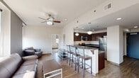 Located at 112 W Commerce St in Youngstown, Ohio, this single-floor unit offers 3 bedrooms, 3 bathrooms, and a thoughtfully designed layout that maximizes functionality. The entrance opens into a clean, light-filled hallway with tile flooring, leading into the heart of the unit. The open-concept living, dining, and kitchen area serves as the central gathering space, featuring wood-look flooring and a ceiling fan overhead. The kitchen is well-appointed with rich dark wood cabinetry, dark countertops, stainless steel appliances including a range, microwave, and refrigerator, and a peninsula with bar seating illuminated by pendant lighting. The living area offers views of the surrounding cityscape through large windows. Each of the three bedrooms features carpeted flooring, multiple windows bringing in ample natural light, and dedicated closet space. The bedrooms provide city views, adding an urban character to the private spaces. All three bathrooms are consistently appointed with dark wood vanities, framed mirrors, tile flooring, and shower-tub combinations. A utility room and additional closets round out the practical features of this well-organized unit, making it a functional and comfortable urban residence.