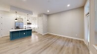 Located at 121 Sams St in Decatur, GA, this thoughtfully designed single-floor space offers a seamless blend of modern style and functional living. The open-concept kitchen and living area serves as the heart of the home, anchored by a striking teal kitchen island with a white quartz countertop and an undermount sink with a matte black faucet. White shaker-style cabinetry lines the walls, complemented by open display shelving and stainless steel appliances, including a French door refrigerator and built-in microwave. Two globe pendant lights hang above the island, adding warmth and character. Light-toned hardwood-style flooring flows throughout, connecting the kitchen to the open living area, which benefits from recessed lighting and a sliding barn door. A door leads to an outdoor balcony, inviting natural light and outside views into the space. The hallway connects the main living areas to the well-appointed bathroom, which features a wide white vanity with ample drawer and cabinet storage, a bold black-framed mirror, and marble-style tile walls and flooring. Matte black hardware and fixtures provide a cohesive, contemporary touch throughout the entire space.