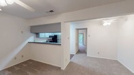 This single-floor 1-bedroom, 1-bathroom residence offers a thoughtfully arranged layout that maximizes functionality and comfort. The open living area features neutral carpet flooring and a ceiling fan with integrated lighting, creating a comfortable and airy atmosphere. A large sliding glass door floods the space with natural light and provides direct views of the surrounding greenery, enhancing the sense of openness.

The kitchen is positioned adjacent to the living area and features a pass-through counter design with dark countertops, light blue cabinetry, and black appliances including a gas range and refrigerator. Wood-look vinyl flooring grounds the kitchen space, providing a practical and attractive contrast to the carpeted living areas.

The bedroom is generously proportioned, complete with plush carpet, a ceiling fan, and a large sliding glass door that offers additional natural light and outdoor views. A dedicated walk-in closet provides ample storage space.

The bathroom is finished with rich wood-look vinyl flooring and includes a full-size soaking tub with a tiled surround, a modern vanity with dark countertops and gray cabinetry, and clean white fixtures throughout. The overall design of this residence is clean, bright, and move-in ready, with consistent finishes that create a cohesive and welcoming living environment.