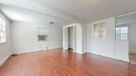 Located at 2613 Crocker St in Houston's vibrant Montrose neighborhood, this single-story space offers a clean, functional layout with consistent warm-toned hardwood-style flooring throughout. The living area is generously proportioned, bathed in natural light from window blinds, and features exposed ceiling beams that add subtle architectural character. White walls create a bright, neutral canvas, while louvered bifold closet doors provide ample built-in storage. A charming built-in cabinet with glass-paned doors serves as a distinctive architectural detail between rooms. The kitchen is well-equipped with white cabinetry, tile countertops and backsplash, a white electric range, refrigerator, and a window that invites natural light into the space. Light hardwood-style flooring in the kitchen complements the rest of the home. The bathroom maintains a crisp, all-white aesthetic with subway tile wainscoting, a vanity with under-cabinet storage, a mirrored medicine cabinet, and tile flooring. The entryway opens into the main living space, offering a welcoming transition into the home. Overall, the space presents a straightforward and practical interior with classic details throughout.