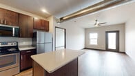 This well-appointed 2-bedroom, 2-bathroom residence at 600 NW Cherrycreek Ln in Ankeny, Iowa offers a thoughtfully designed single-level layout with modern finishes throughout. Wood-look flooring flows consistently across the entire space, complemented by crisp white walls and dark contrasting baseboards and door trim that give the home a clean, contemporary aesthetic.

The open-concept kitchen and living area serves as the heart of the home. The kitchen is outfitted with rich dark cabinetry, light quartz-style countertops, a central island with additional prep space, stainless steel appliances including a refrigerator, range, microwave, and dishwasher, and open wall shelving for added storage and display.

Both bedrooms are generously sized, with the primary bedroom offering a comfortable and spacious retreat. Each bedroom features ceiling fans with integrated lighting, natural light from windows with exterior views, and direct access to walk-in closets with wire shelving systems. Exposed ductwork in the bedrooms adds an industrial design touch.

The two bathrooms mirror each other in style, each featuring a dark-framed vanity mirror, undermount sink, light countertops, and wood-look flooring. One bathroom provides direct walk-in closet access, enhancing the functionality of the primary suite. The overall layout is efficient and practical, making excellent use of every square foot.