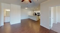 This single-floor residence offers a thoughtfully designed open-concept layout that seamlessly connects the living area to the kitchen. Rich, dark hardwood-style flooring flows throughout the main living spaces, while plush carpeting adds warmth and comfort to the bedrooms. Ceiling fans are present throughout, enhancing airflow and comfort in every room.

The kitchen is a standout feature, outfitted with crisp white cabinetry, granite countertops, stainless steel appliances including a refrigerator, range, and microwave, and a central island with a built-in sink. Pendant lighting illuminates the workspace, and the open design allows for easy interaction with the living area.

The living space is bright and open, with a sliding glass door that invites natural light and provides access to the outdoors. Multiple bedrooms offer generous proportions, each featuring ceiling fans and plush carpeting. At least one bedroom includes a walk-in closet with shelving for ample storage.

The bathrooms are finished with granite-topped white vanities, tiled tub-shower combinations, and wood-style flooring, maintaining a consistent, clean aesthetic throughout. The overall design is neutral and modern, creating a move-in-ready space that is both functional and inviting.
