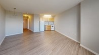Located at 1320 W Somerville Ave in Philadelphia's 19141 neighborhood, this single-floor unit offers a straightforward and functional layout. The main living area is open and generously proportioned, featuring light-toned luxury vinyl plank flooring that runs throughout, neutral gray walls, and clean white trim. A pendant light fixture adds a simple decorative touch to the open space, while baseboard heating provides efficient climate control.

The kitchen is efficiently designed and integrated into the main living space. It features warm honey-toned wood cabinetry — both upper and lower — a single-basin sink with a modern faucet, a compact gas range, and a full-size refrigerator. Under-cabinet fluorescent lighting illuminates the work surface, making the kitchen practical for everyday use.

The bathroom is clean and simply appointed, with white ceramic tile wainscoting lining the walls, gray speckled vinyl flooring, and a full tub-shower combination with a curtain rod. A vanity with under-sink storage, a wall-mounted mirror, and a baseboard heater complete the space. The overall aesthetic throughout the unit is neutral and move-in ready, providing a functional foundation in a residential Philadelphia neighborhood.