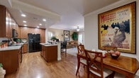 This single-story, 2-bedroom, 3-bathroom home offers a thoughtfully designed open-concept layout that seamlessly connects the kitchen, dining area, and living room. The kitchen is a functional centerpiece, featuring warm wood cabinetry, granite countertops, a breakfast bar with seating for three, recessed lighting, and black appliances including a full-size refrigerator. Adjacent to the kitchen, the dining area is framed by hardwood flooring and offers an intimate setting for meals. The living room flows naturally from the dining space, complete with a ceiling fan and access to a patio door, inviting natural light throughout.

Crown molding and consistent hardwood flooring unify the main living areas, lending a polished, cohesive aesthetic. The primary bedroom is a comfortable retreat, featuring plush carpet, multiple windows, a ceiling fan, and mirrored sliding closet doors. The second bedroom is equally well-appointed with similar finishes. The three bathrooms include a tiled tub-shower combination with glass doors and oil-rubbed bronze fixtures.

Additional highlights include a dedicated in-unit laundry room with side-by-side washer and dryer, a private patio for outdoor relaxation, and two hallways that provide efficient flow throughout the home.