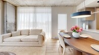 Located at 1555 Boul Chomedey in Laval, this well-appointed 3-bedroom, 2-bathroom unit offers a thoughtfully designed single-level layout with modern finishes throughout. Light hardwood flooring flows consistently across the space, complemented by crisp white walls and an airy, neutral palette.

The open-concept kitchen is a standout feature, showcasing flat-front taupe cabinetry extending to the ceiling, a generous waterfall island with an integrated undermount sink and matte black faucet, stainless steel appliances, and sleek linear pendant lighting. The kitchen opens seamlessly to the dining and living areas, where exposed concrete ceilings and large windows dressed in sheer curtains create a bright, loft-inspired ambiance with ample natural light.

The primary bedroom offers a comfortable, well-proportioned retreat. Additional bedrooms benefit from the same concrete ceiling detail and generous natural light through sheer-draped windows. Two bathrooms serve the unit: one features a soaker tub, large-format tile, a wood-tone floating vanity with a backlit round mirror, and dark accent walls; the other offers a glass-enclosed shower with matte black fixtures and tile surround. The welcoming entryway features a round decorative mirror and direct sightlines to the kitchen, setting the tone for the unit's cohesive modern aesthetic.