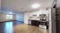 Located at 20 Day St in Norwalk, CT, this one-bedroom, one-bathroom residence offers a functional and well-appointed single-floor layout. Rich, dark hardwood-style flooring flows throughout the main living areas, complementing the neutral, light-toned walls and dark baseboards that give the space a clean, modern aesthetic.

The open kitchen and living room area is designed for both comfort and practicality. The kitchen features a two-tone cabinetry arrangement — crisp white upper cabinets paired with dark espresso lower cabinets — topped with light countertops. Stainless steel appliances, including a range, microwave, and dishwasher, complete the space.

The living area benefits from large multi-pane windows fitted with blinds, allowing natural light to fill the room while offering views of the surrounding neighborhood. A flush-mount light fixture provides additional illumination.

The bedroom is generously sized, continuing the hardwood-style flooring and featuring a large window that brings in natural light and outdoor views. The full bathroom is finished with neutral tile flooring, a white vanity with shaker-style cabinetry, and a full tub/shower combination with brushed nickel fixtures.

A dedicated laundry room includes in-unit washer and dryer hookups and overhead wire shelving, providing practical storage and added convenience.