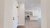 Located in the desirable Porter Ranch neighborhood of Los Angeles, this well-appointed single-story home offers three bedrooms, two bathrooms, and a thoughtfully designed open floor plan. The entrance leads directly into a bright, open-concept kitchen and living area, where warm wood-look flooring, recessed lighting, and pendant lights over the island create a modern yet welcoming atmosphere. The kitchen is outfitted with gray shaker cabinetry, white quartz countertops, a subway tile backsplash, and a full suite of stainless steel appliances, including a refrigerator, range, microwave, and dishwasher. A central island provides additional prep and seating space. The bedrooms are carpeted and bathed in natural light, with ceiling fans and clean white walls offering a calm, neutral environment. The primary bedroom includes a dedicated closet. Both bathrooms feature light tile flooring and contemporary black hardware accents; one includes a sleek sliding glass shower-tub enclosure, while the other offers an open, airy layout with built-in shelving and a window. Three hallways connect the rooms efficiently throughout the home. The overall design is clean and modern, emphasizing neutral tones, quality finishes, and functional living spaces.
