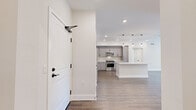 Located in the desirable Porter Ranch neighborhood of Los Angeles, this well-appointed single-story home offers three bedrooms, two bathrooms, and a thoughtfully designed open floor plan. The entrance leads directly into a bright, open-concept kitchen and living area, where warm wood-look flooring, recessed lighting, and pendant lights over the island create a modern yet welcoming atmosphere. The kitchen is outfitted with gray shaker cabinetry, white quartz countertops, a subway tile backsplash, and a full suite of stainless steel appliances, including a refrigerator, range, microwave, and dishwasher. A central island provides additional prep and seating space. The bedrooms are carpeted and bathed in natural light, with ceiling fans and clean white walls offering a calm, neutral environment. The primary bedroom includes a dedicated closet. Both bathrooms feature light tile flooring and contemporary black hardware accents; one includes a sleek sliding glass shower-tub enclosure, while the other offers an open, airy layout with built-in shelving and a window. Three hallways connect the rooms efficiently throughout the home. The overall design is clean and modern, emphasizing neutral tones, quality finishes, and functional living spaces.
