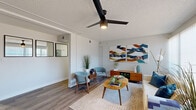 This single-floor residence showcases a cohesive mid-century modern design complemented by contemporary updates. The living area serves as the heart of the home, featuring light wood-look flooring, a textured ceiling with a sleek black ceiling fan, and large sliding glass doors that invite abundant natural light and provide outdoor views. The open layout connects seamlessly to a dining area, enhancing the sense of spaciousness.

The galley-style kitchen is well-appointed with white shaker cabinetry, black hardware, white quartz countertops, stainless steel appliances, and light wood-look flooring. A window at the far end brings in additional natural light.

Two bedrooms offer comfortable retreats, each featuring the signature shiplap-style accent walls, wood-look flooring, and large windows with vertical blinds that frame outdoor views. Both rooms provide ample space for furnishings.

Two bathrooms mirror the home's clean aesthetic, finished with white vanities, quartz countertops, black fixtures, and framed mirrors. One bathroom includes a tub-shower combination, while the second features a glass-enclosed walk-in shower, offering practical variety throughout the residence.