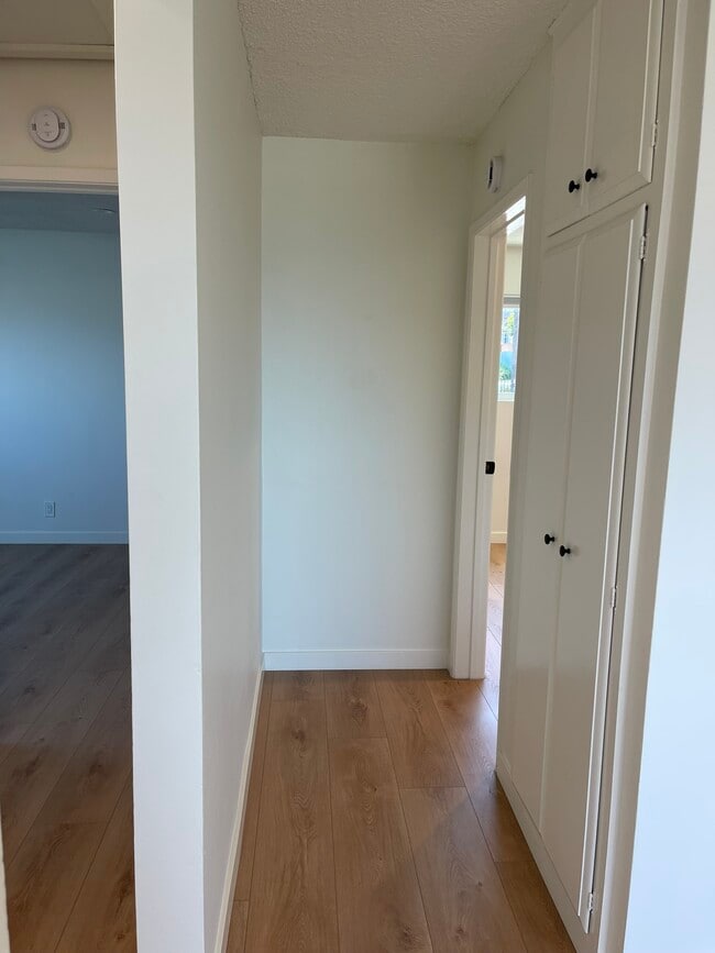 Hallway outside smaller bedroom. Note coat closet and cupboards. - 1039 6th St