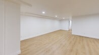 Located at 1216 Avenue Rd in Toronto's desirable Avenue Road corridor, this thoughtfully renovated one-bedroom, one-bathroom unit offers a clean, modern aesthetic throughout. Light-toned hardwood flooring flows seamlessly across the main living areas, complementing the crisp white walls and recessed pot lighting that brighten the space.

The expansive living area is generously proportioned, featuring baseboard heating, a wall-mounted ductless split system for year-round climate control, and egress windows that allow natural light to filter in. The open layout lends itself well to flexible furniture arrangements.

The kitchen is finished with white shaker-style cabinetry, light stone countertops, ample upper and lower storage, and a double stainless steel sink with a matte black faucet — a refined contrast to the bright cabinetry. A small window above the sink adds a touch of natural light to the space.

The bedroom is a comfortable, well-proportioned room with light hardwood floors, recessed lighting, and a built-in double closet with sleek, flush panel doors offering generous storage.

The bathroom is stylishly appointed with a natural wood vanity, a dark matte integrated sink with matching black fixtures, an arched mirror, and contemporary wall-mounted lighting — all set against large-format white tile flooring for a polished finish.