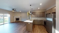 This single-floor residence offers a well-designed open-concept layout that seamlessly connects the kitchen and living areas. The kitchen serves as a central hub, showcasing warm taupe cabinetry, light granite countertops, and a central island with a built-in sink illuminated by stylish pendant lighting. Stainless steel appliances, including a refrigerator, range, and microwave, complete the space. Recessed lighting and hardwood-style flooring extend throughout, lending a cohesive, modern feel.

The adjoining living area features a ceiling fan and a stone-surround fireplace that anchors the room as a focal point, adding warmth and character. Bedrooms are carpeted for comfort, with natural light provided through multiple windows fitted with blinds. Each bedroom benefits from generous walk-in closet space outfitted with wire shelving systems for organized storage.

The bathrooms are finished with granite-topped vanities and wood-tone cabinetry. One bathroom includes a tub-shower combination and hardwood-style flooring. A dedicated en-suite bathroom connects directly to a bedroom, offering added privacy. Throughout the residence, neutral wall tones, clean trim work, and consistent finishes contribute to a cohesive, move-in-ready aesthetic.