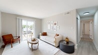 This single-floor residence offers a cohesive, modern aesthetic defined by neutral warm-gray tones, light-toned flooring, and clean white trim throughout. The living room serves as a welcoming centerpiece, featuring light hardwood-style flooring, a curated gallery wall, and a sliding glass door that opens to a private outdoor balcony, filling the space with natural light. Adjacent to the living area, a dedicated dining nook provides an intimate setting illuminated by a striking orb-style chandelier, accented by framed botanical artwork on the walls. The galley-style kitchen is well-equipped with stainless steel appliances, including a refrigerator, electric range, built-in microwave, and dishwasher, all complemented by white cabinetry with matte black hardware, a subway tile backsplash, and light stone countertops. The residence includes multiple carpeted bedrooms, each fitted with ceiling fans, natural light from window blinds, and generous floor space. One bedroom features an adjoining bathroom with white cabinetry and matte black fixtures. Additional bathrooms are finished consistently with white vanities and modern hardware. The overall layout, visible in the dollhouse view, is efficiently organized and thoughtfully designed for comfortable everyday living.